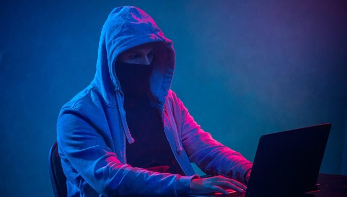 hooded-computer-hacker-stealing-information-with-laptop-scaled