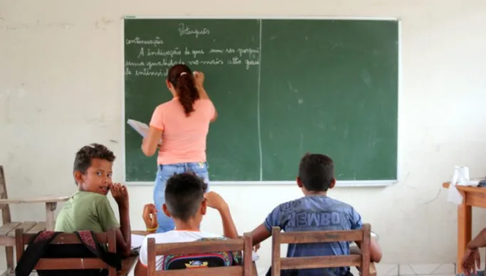 Alunos e professora em sala de aula de escola rural
