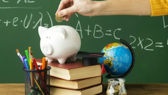 pessoa-colocando-moedas-no-cofrinho-com-livros-e-lapis_220520230118.jpg
