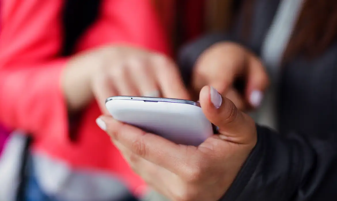 two-beautiful-students-using-mobile-phone-street_0